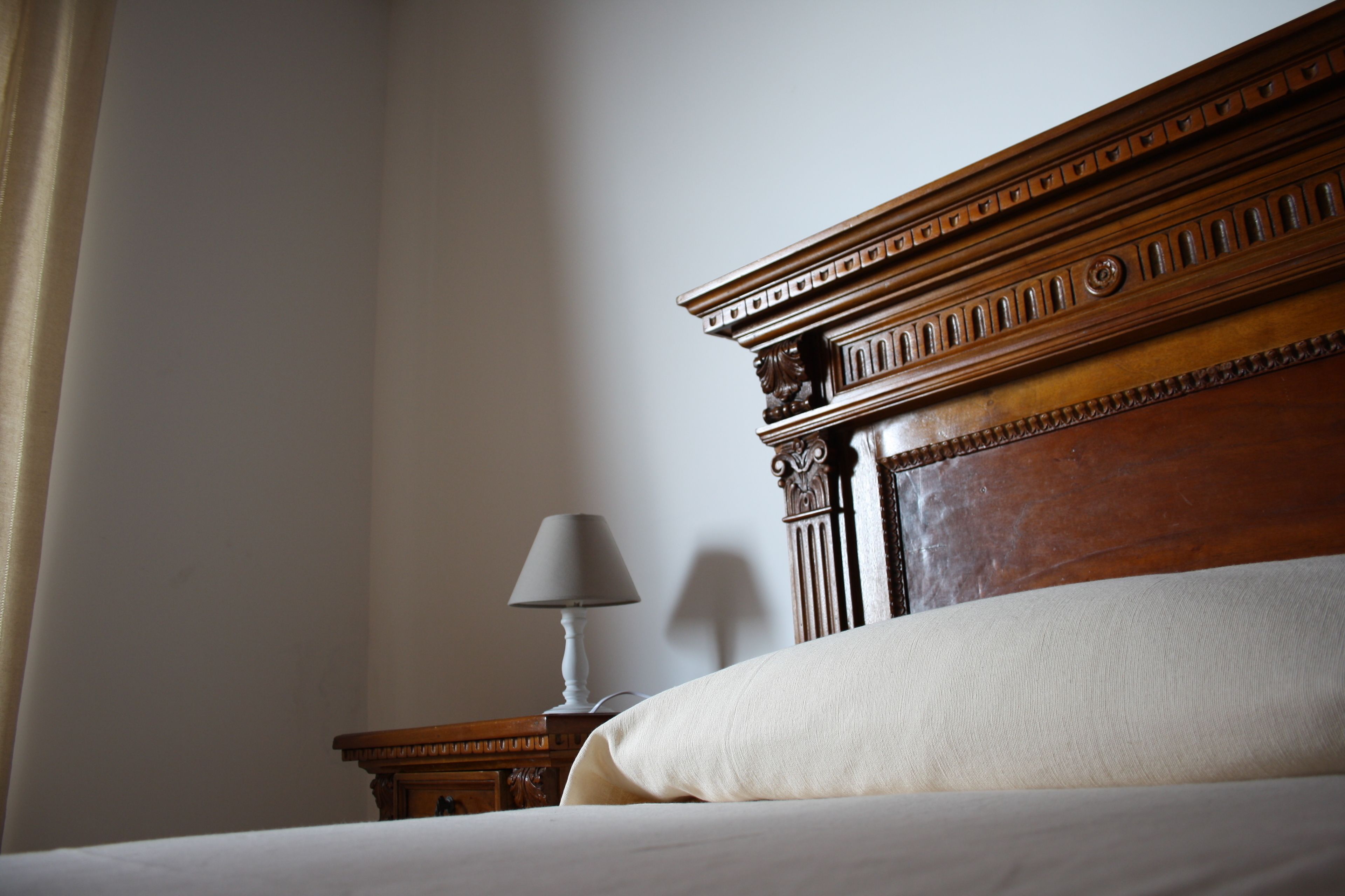 Un lit bien fait, avec une tête de lit en bois, une table de chevet avec une lampe et un mur sobre.