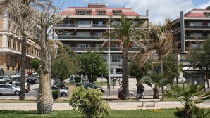 A multi-story hotel with balconies, palm trees, and a parking area. - La Casa sul Mare (Civitavecchia)