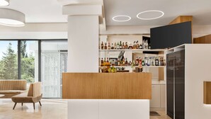 A modern bar area with a wooden counter, shelves of liquor bottles, and a seating area with a sofa and chairs.