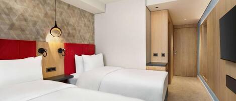 A hotel room with two beds, a red accent wall, a wooden headboard, a wall-mounted TV, and a modern light fixture.