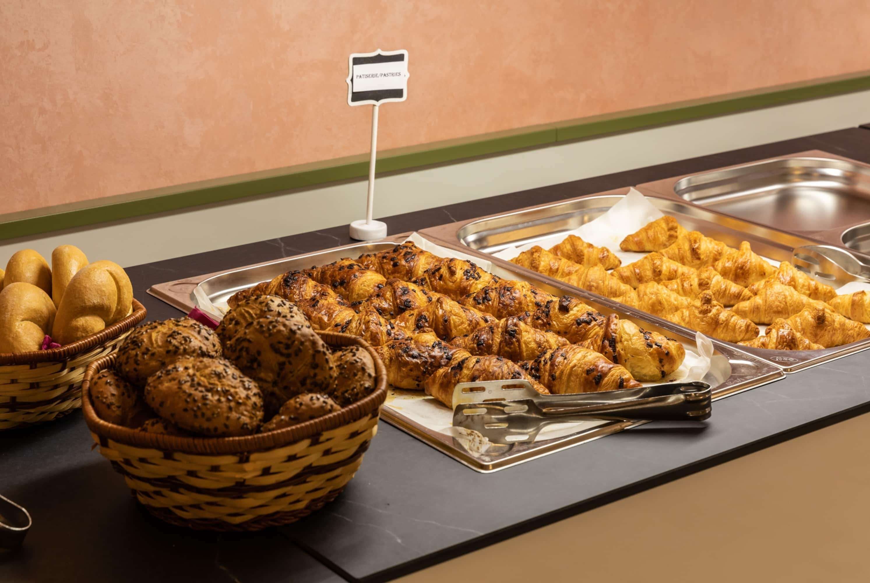 Un bufé con diversas opciones de panadería, incluyendo pan, croissants y bollos.