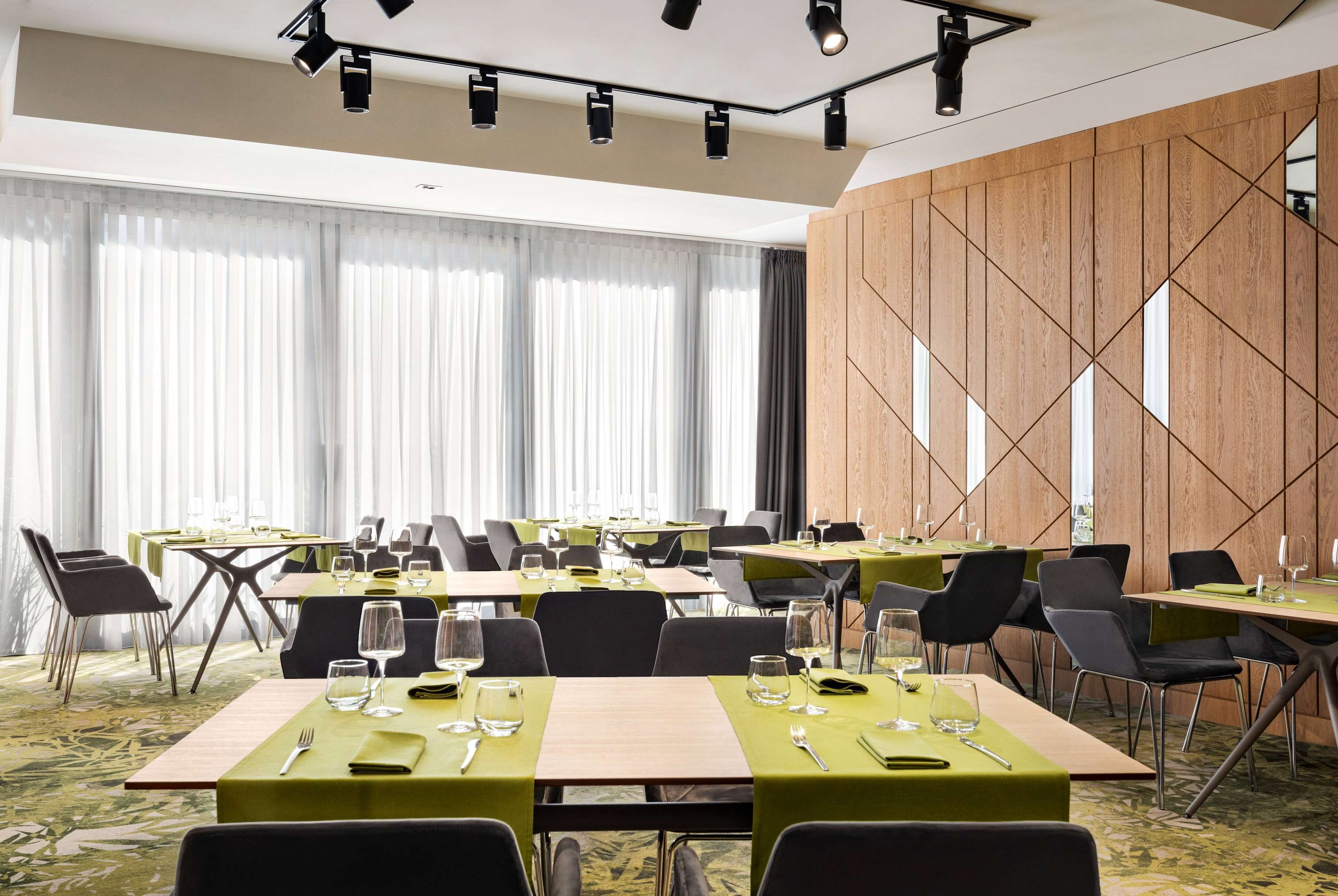 A conference room with multiple tables, chairs, and a wooden accent wall.