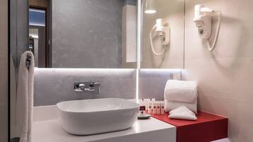 Un bagno moderno con un grande specchio, un lavandino bianco e un piano d'appoggio rosso.