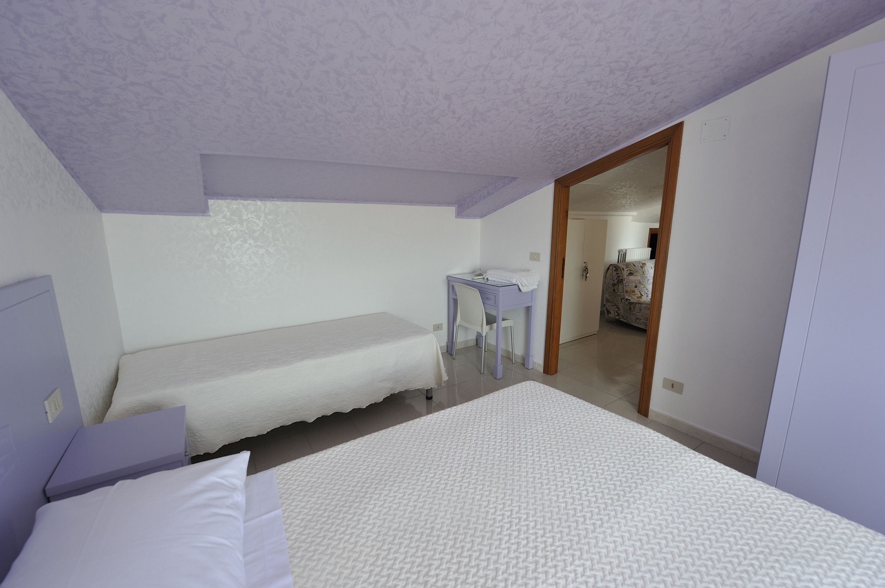 Una camera da letto con un letto singolo, una scrivania e una sedia.