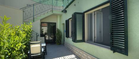 Un patio con una escalera, una silla y una planta en maceta.