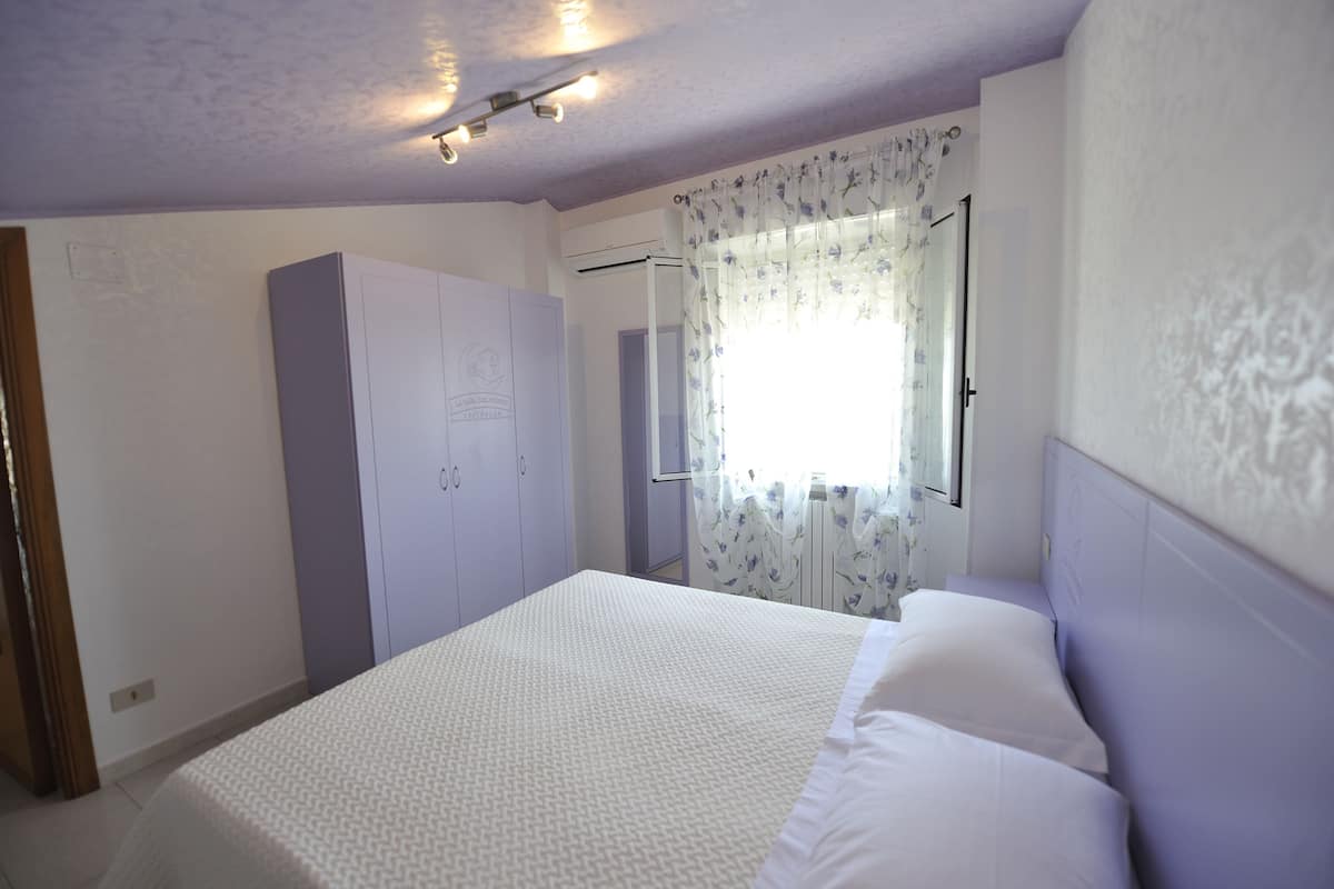 Ein Schlafzimmer mit einem Bett, einem Kleiderschrank und einem Fenster mit Vorhängen.