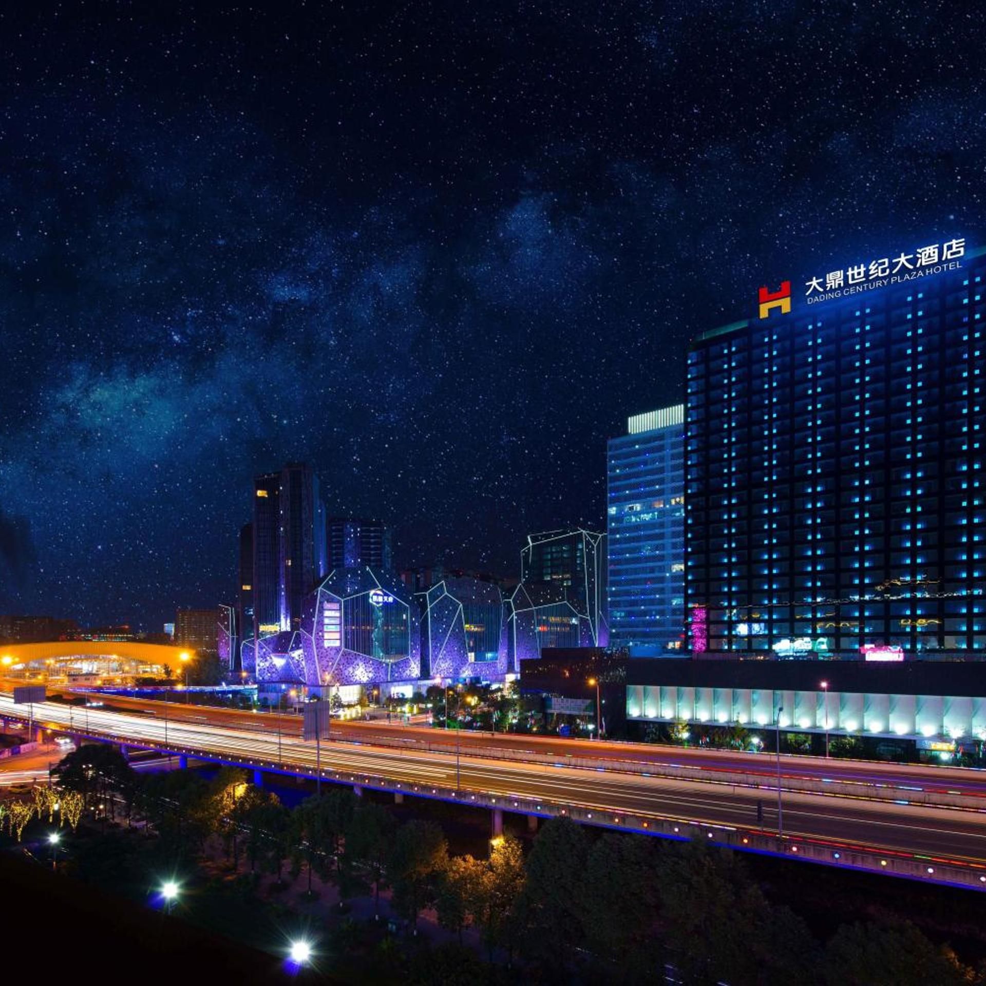 A night view of a cityscape with a prominent hotel building featuring illuminated signage.