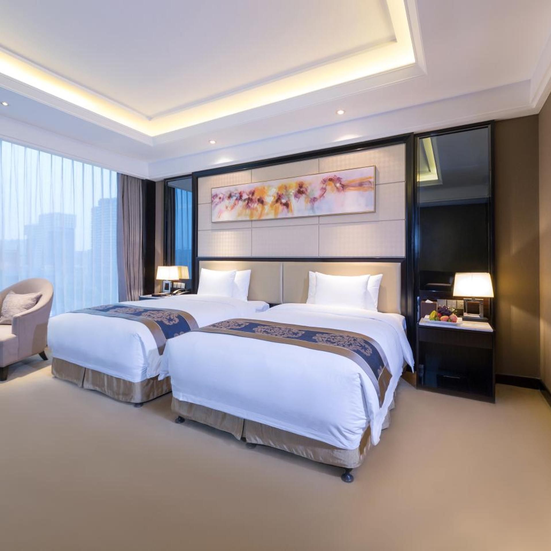A hotel room with two beds, a large window, and a city view.