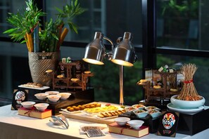 Una mesa de buffet con diversos platos, una planta decorativa y un par de lámparas.