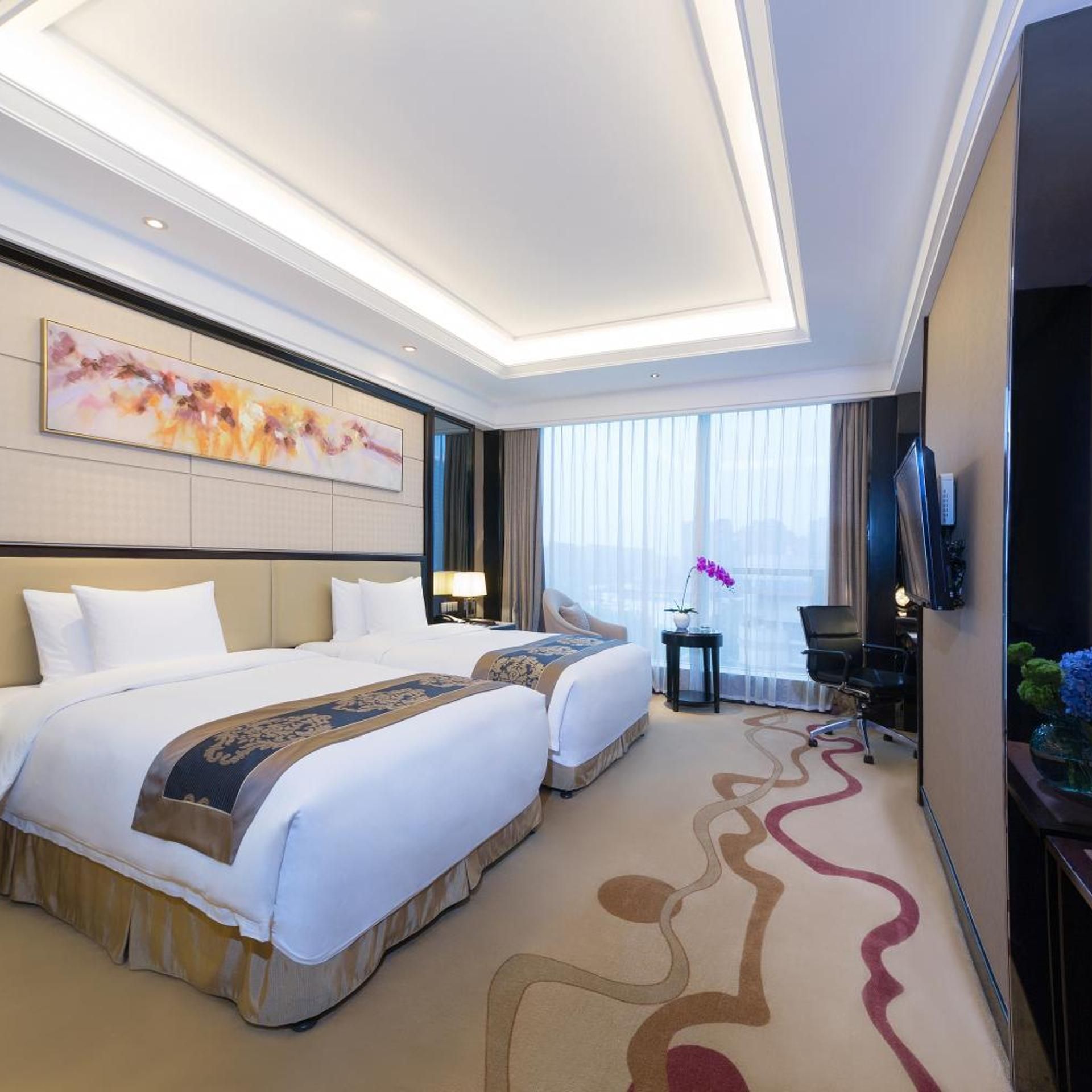 A hotel room with two beds, a large window, a flat-screen TV, and a decorative wall piece.