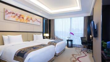 A hotel room with two beds, a large window, a flat-screen TV, and a decorative wall piece.