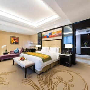 A hotel room with a large bed, a desk, a chair, a sofa, a nightstand, and a decorative wall piece. - Dading Century Plaza Hotel (Chengdu)