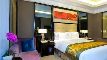 Een hotelkamer met een groot bed, een slaapbank, een nachtkastje, een lamp en een decoratieve spiegel.