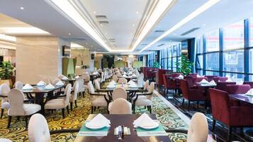 A hotel dining area with long tables, chairs, and a patterned carpet.