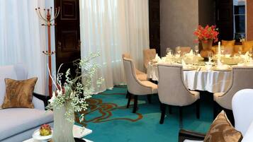 Un comedor con una mesa dispuesta para una comida, un sofá con cojines y un jarrón decorativo con flores.