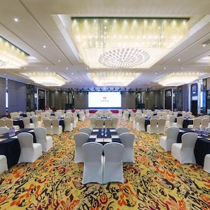A conference room with rows of tables and chairs, a large screen at the front, and a patterned carpet. - Dading Century Plaza Hotel (Chengdu)