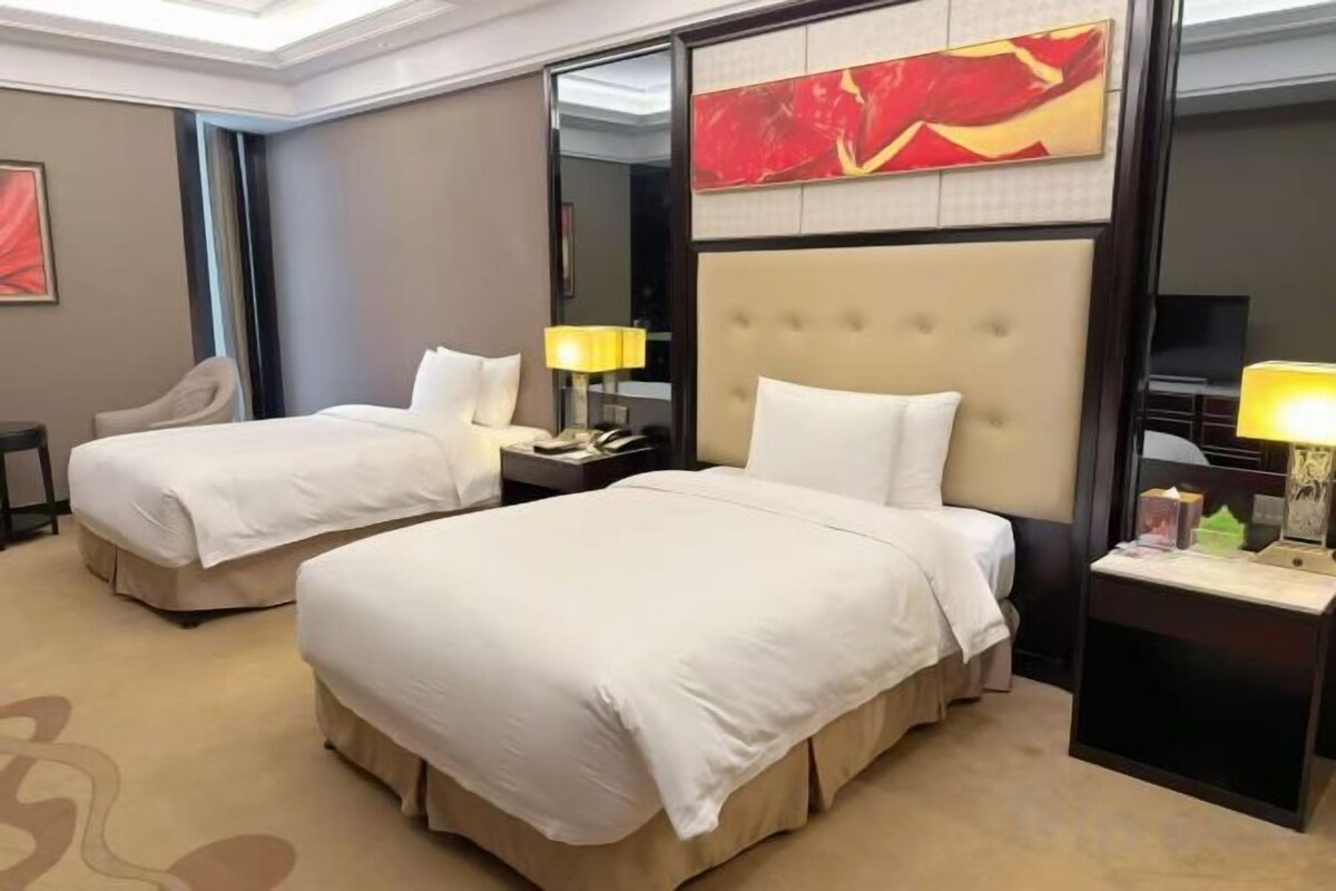 A hotel room with two beds, a large mirror, and a television.