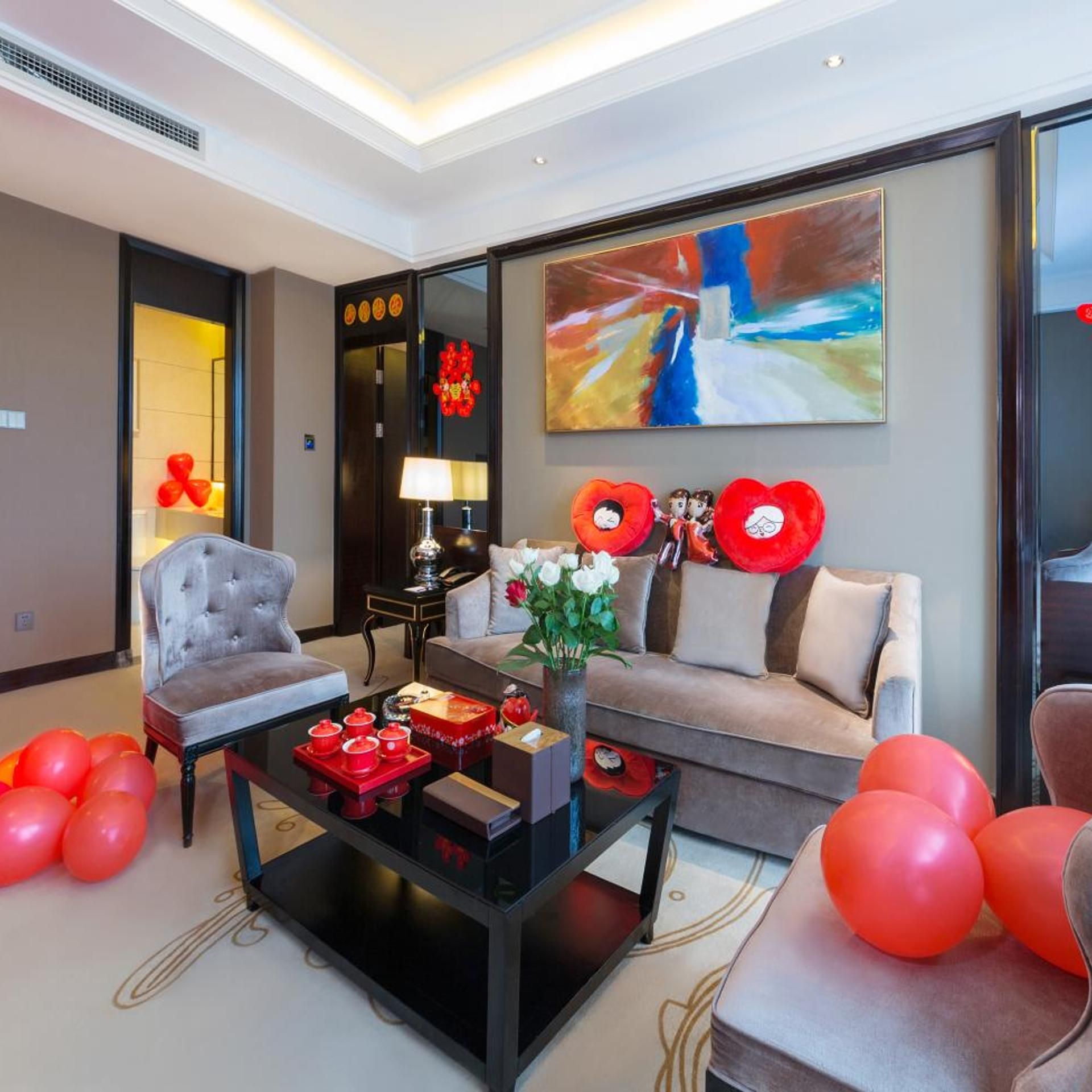 A modern living room with a sofa, armchairs, a coffee table, and a painting on the wall.