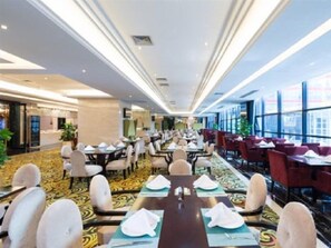 A hotel dining area with tables set for service, large windows, and a carpeted floor. - Dading Century Plaza Hotel (Chengdu)