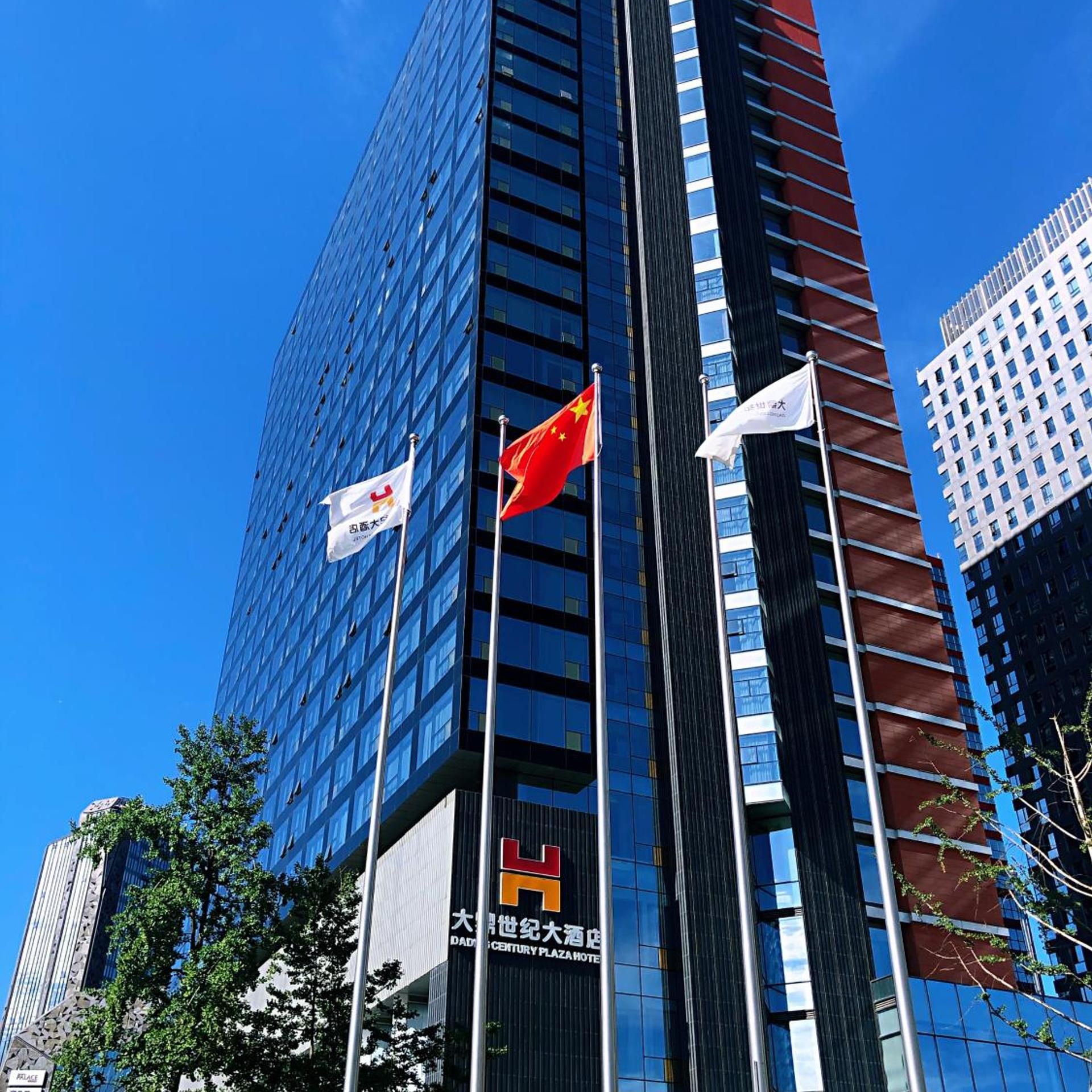 A high-rise building with multiple flags, including the Canadian and Chinese flags, and a sign for the Century Plaza Hotel.