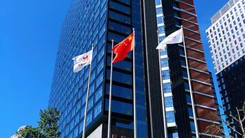 A high-rise building with multiple flags, including the Canadian and Chinese flags, and a sign for the Century Plaza Hotel.