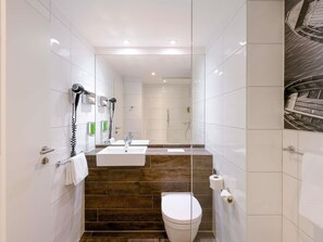 Une salle de bain moderne Ă©quipĂ©e dâune douche, de toilettes et dâun lavabo.