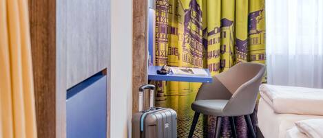 Una habitación de hotel con cama, escritorio, silla y maleta.