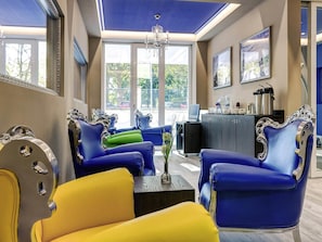 A room with blue and yellow chairs, a desk, and a chandelier.