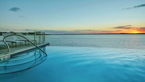 Una piscina con vistas a la puesta de sol sobre el agua.