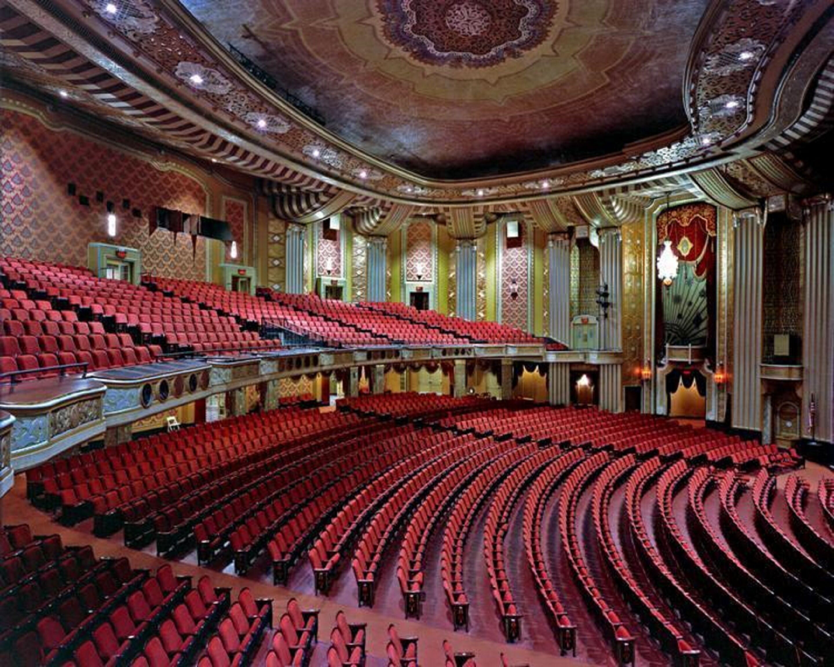 Un teatro ornamentado con asientos rojos y un techo decorativo imponente.