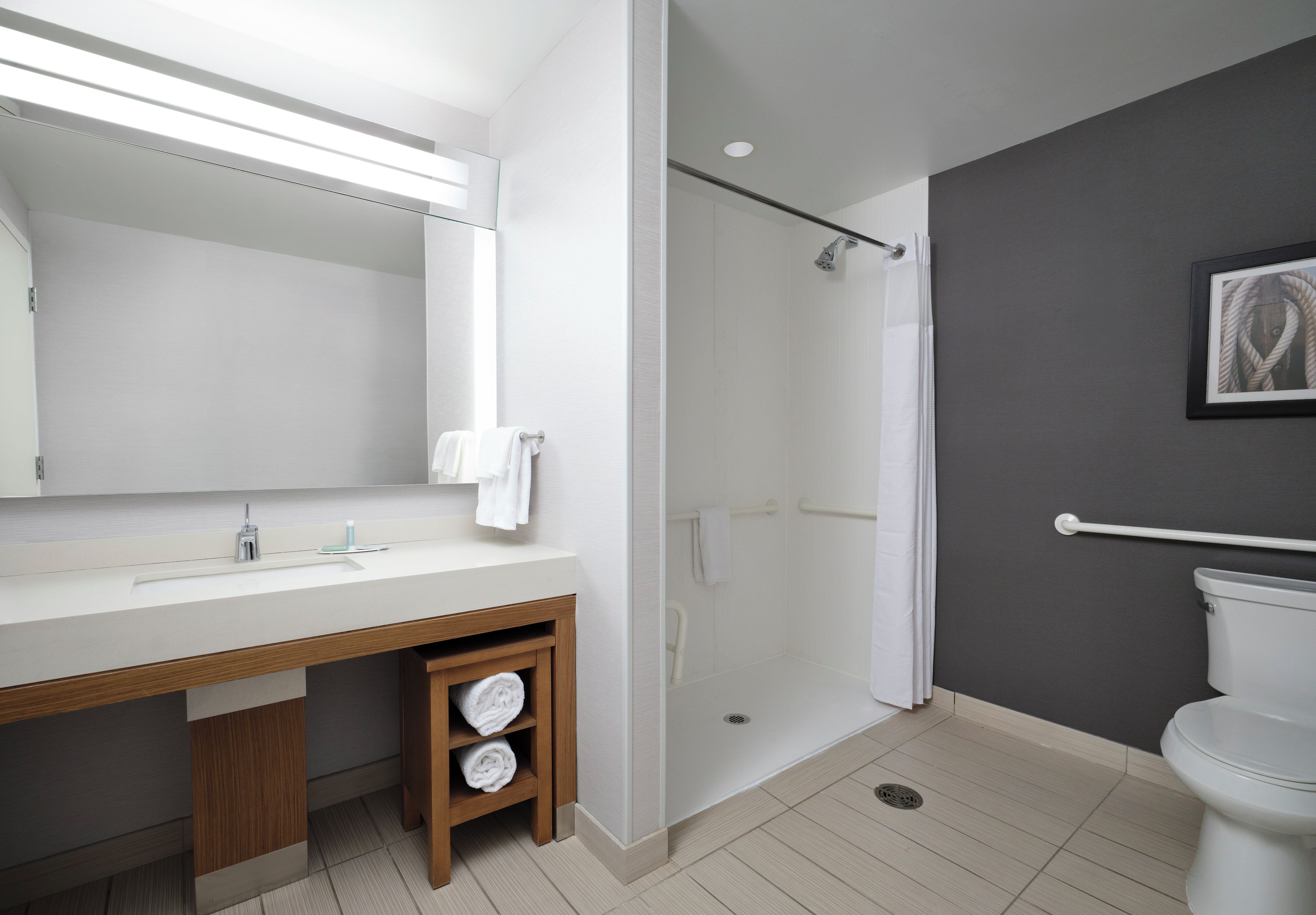 A modern bathroom with a large mirror, a shower, and a toilet.