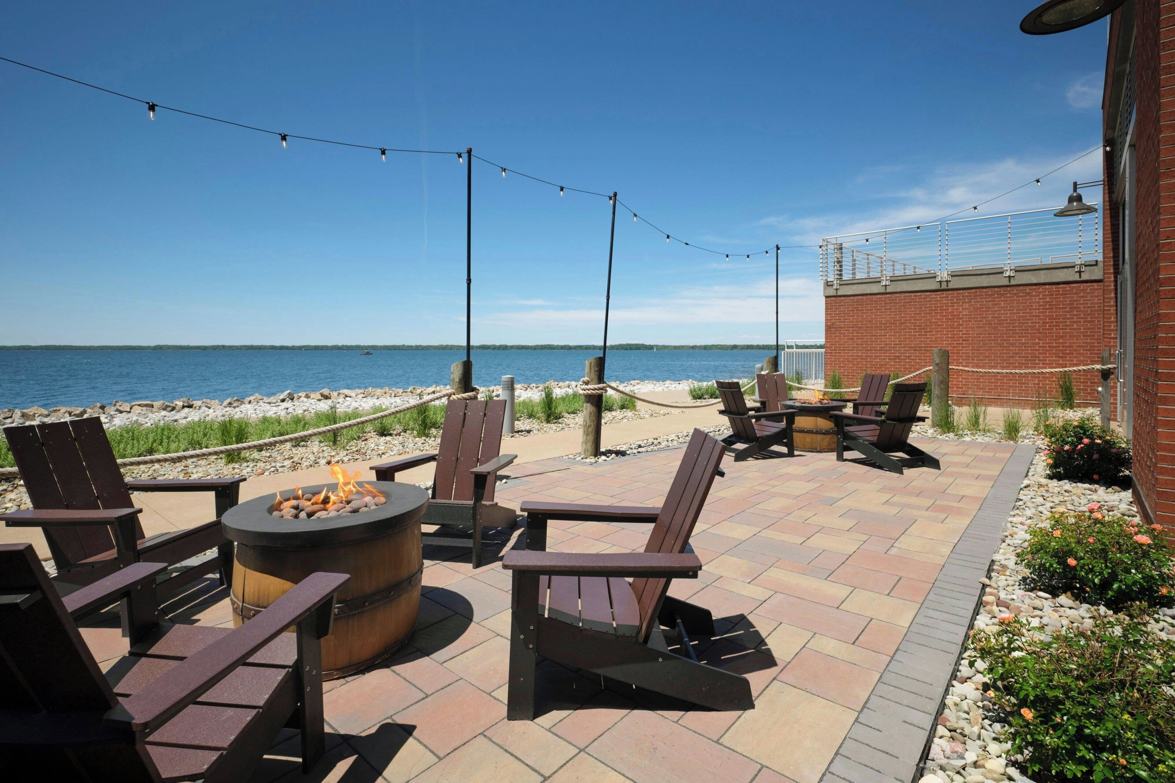 Un patio exterior con sillas Adirondack, una fogata y vistas al océano.