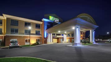 A Holiday Inn Express & Suites hotel with a well-lit entrance and a parking lot.