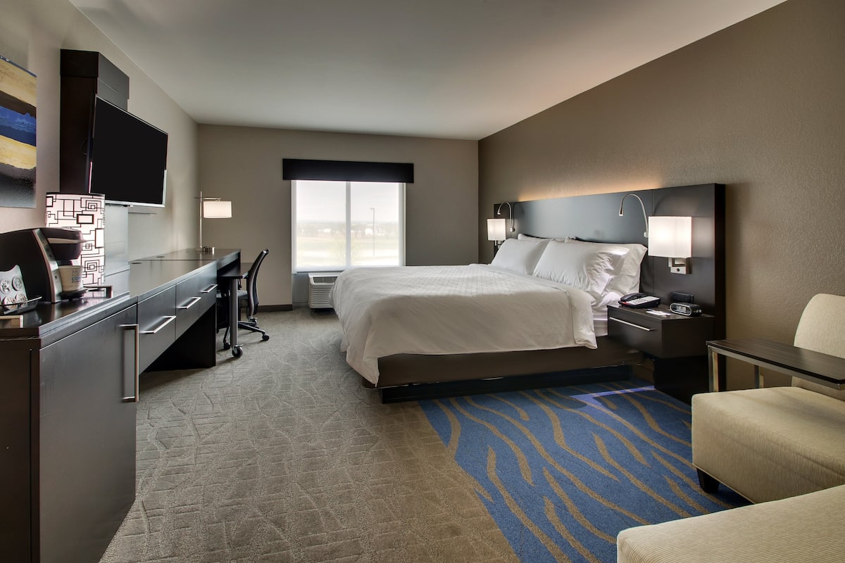 Habitación de hotel con cama, escritorio, silla y televisor.