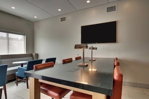 A conference room with a large table, chairs, a projector, and a screen.