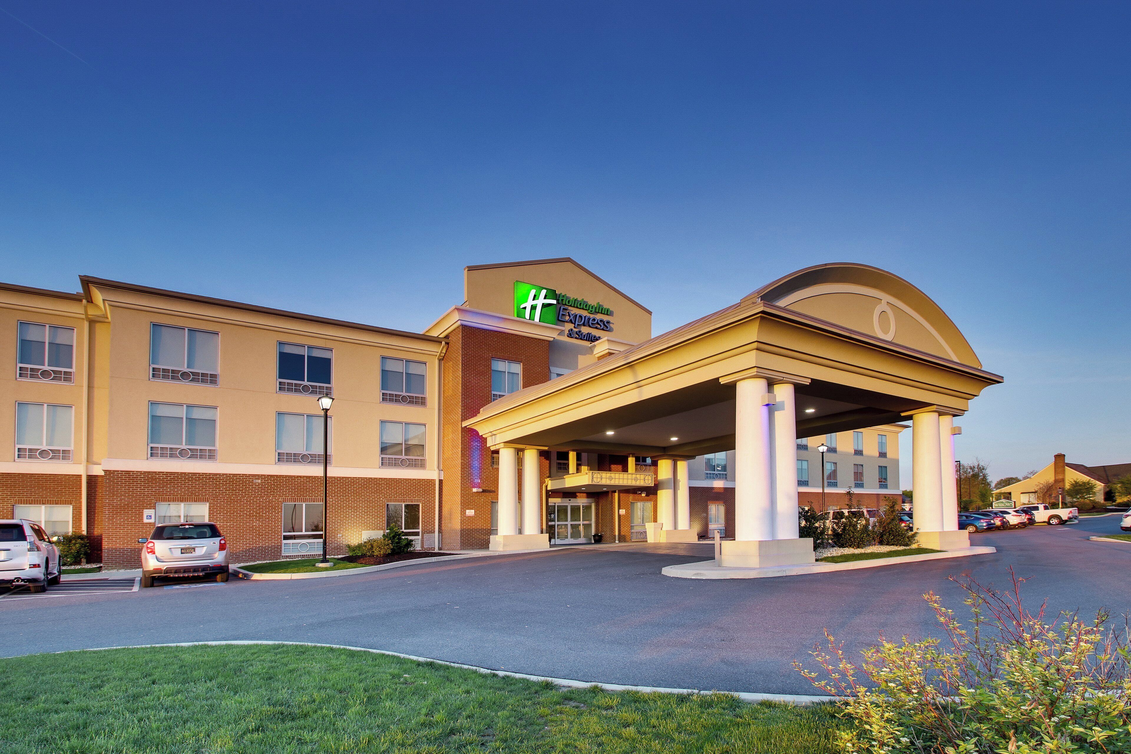 A hotel with a covered entrance, a brick facade, and a sign for 'Holiday Inn Express & Suites'.