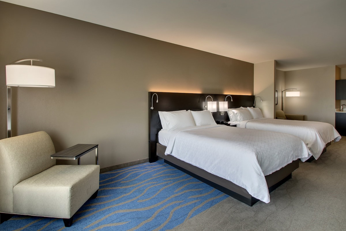 Habitación de hotel con dos camas, un sofá, un escritorio y una lámpara.