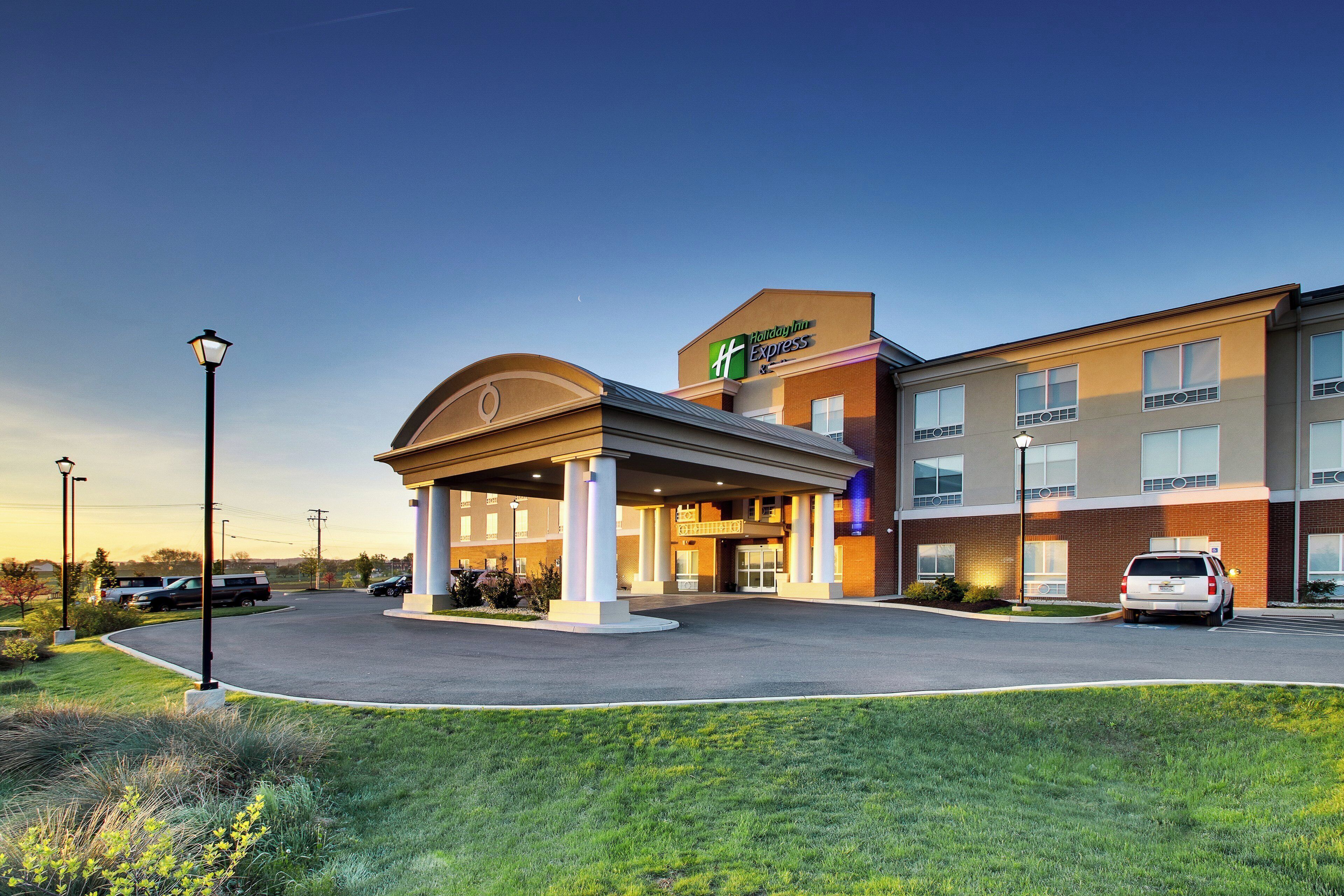 Et Holiday Inn Express hotel med et overdækket indgangsparti, parkeringsplads og en klar himmel.