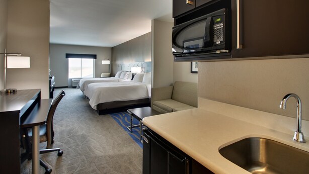 Een hotelkamer met een bed, een bank, een bureau, een magnetron en een wastafel.
