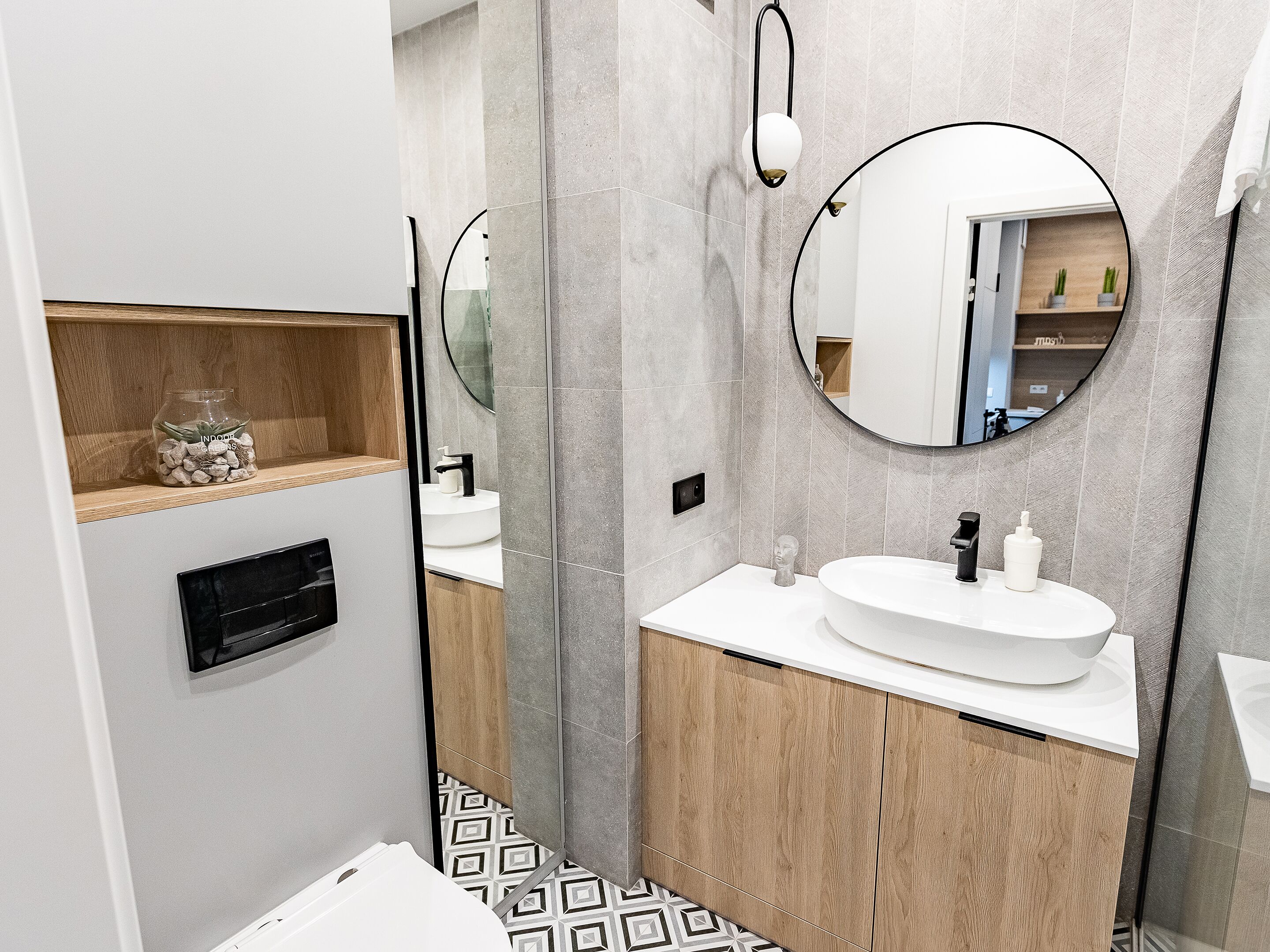 Une salle de bain moderne avec un lavabo blanc, un meuble-lavabo en bois et un grand miroir.