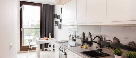 A modern kitchen with white cabinets, a black sink, and a dining area with a white table and chairs.