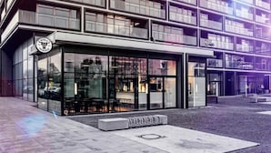 Een modern gebouw met een glazen gevel, een zichtbaar restaurant of café en een fietsenstalling.
