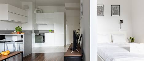 Un apartamento moderno y funcional con kitchenette, comedor y habitación.