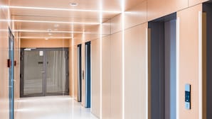 Een modern liftgedeelte met glazen deuren, een bedieningspaneel en een schone, goed verlichte hal.