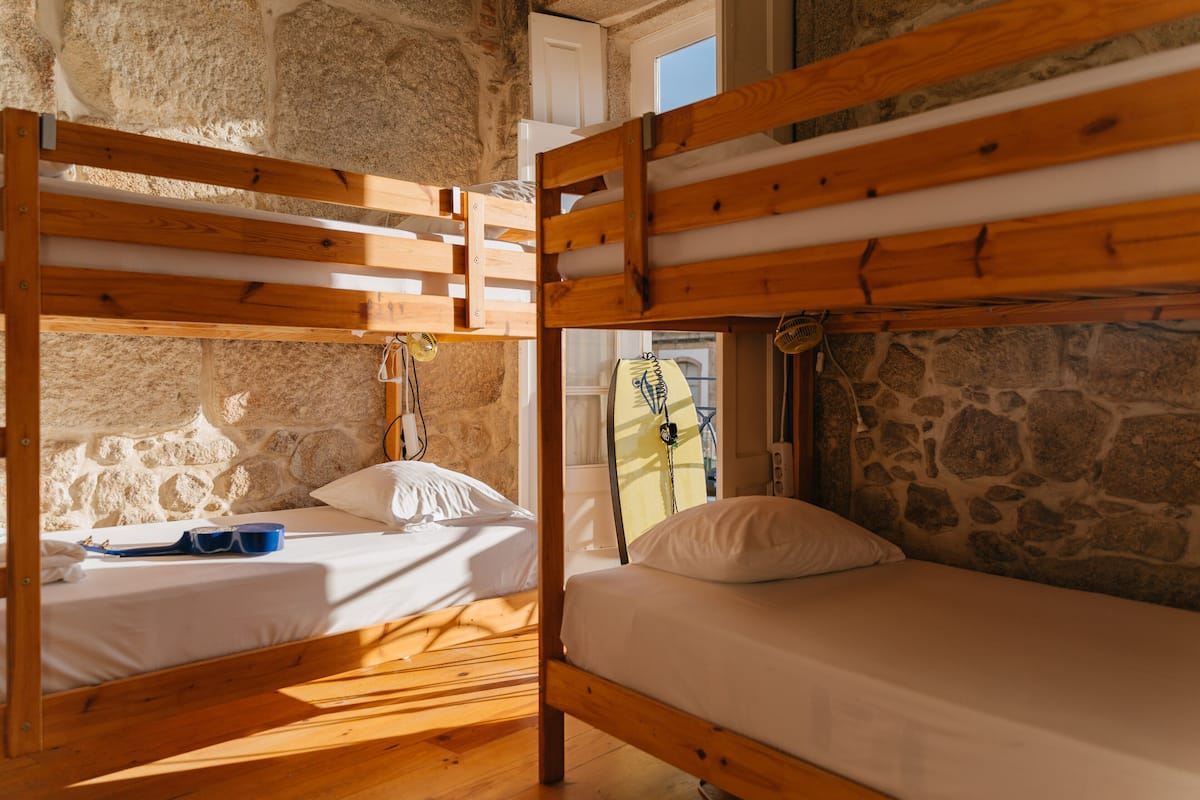 Ein rustikales Zimmer mit Stockbetten, Steinwänden und einem Fenster.