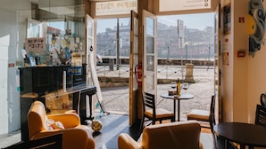 Um saguão de hotel com parede de vidro, balcão de recepção e áreas de estar.
