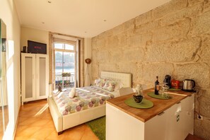A bedroom with a bed, a desk, a wardrobe, and a stone wall. - Happy Porto Hostel & Apartments (Porto)