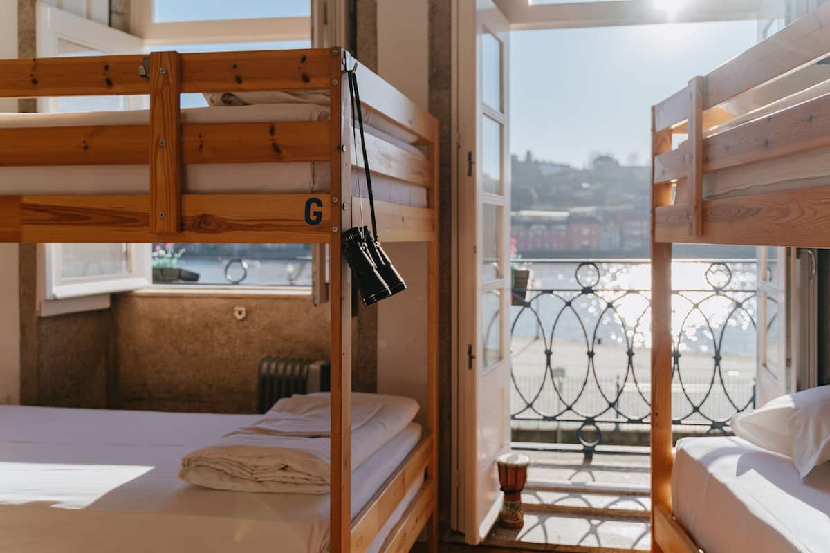 Ein Zimmer mit zwei Etagenbetten, einem Fenster mit Blick auf eine Stadtlandschaft und einem kleinen Tisch mit einem dekorativen Gegenstand.