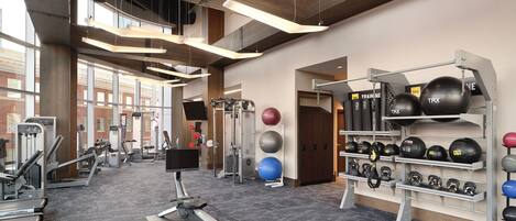 Un gimnasio con equipo de cardio, máquinas de pesas y pelotas de ejercicio.