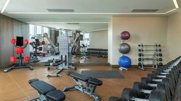 A gym with various exercise equipment, including dumbbells, a bench, and a treadmill.